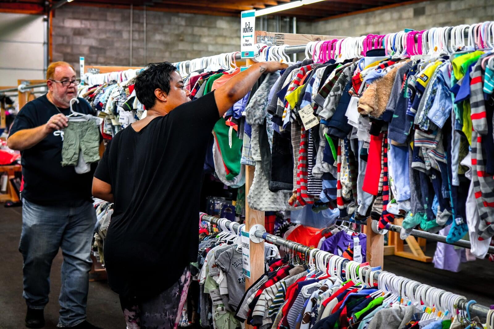 Sellers placing their baby clothing on the racks at a JBF sale.